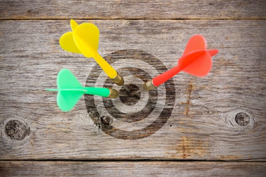 Three darts  hitting target on a wooden planks