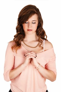 A lovely young woman standing for white background with her hands folded.and eyes closed, praying..