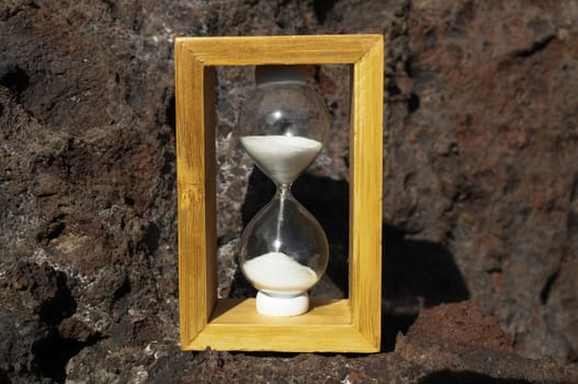 Time Concept White Sand Hourglass on the Volcanic Rocks