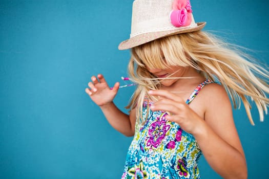 Portrait of stylish cute young girl being playful outside against blue wall background