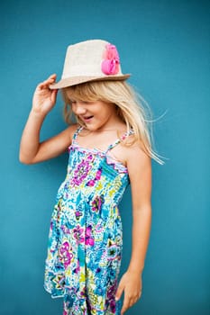 Portrait of stylish cute and happy young girl outside against blue wall background