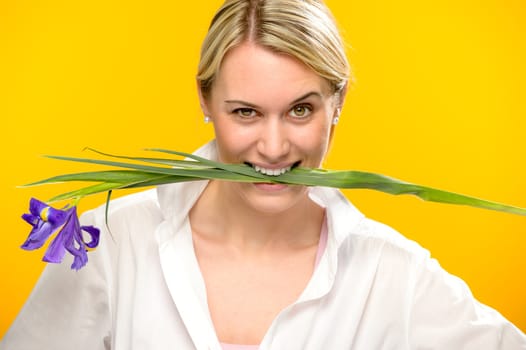 Woman with blue spring iris flower bite between her teeth