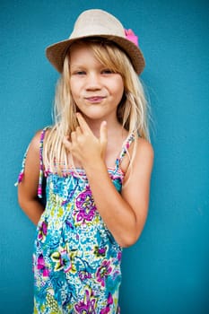 Portrait of stylish cute young girl with smirk expression outside against blue wall background