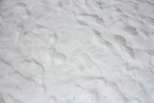 Closeup background view of ninety-nine percent fine grain powdery white gray quartz Siesta Beach, Florida sand outside on a sunny day..