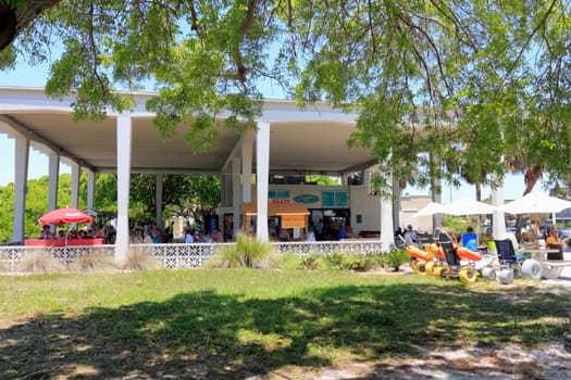 SIESTA KEY, FLORIDA - MAY 9, 2013: Large covered concession stand serving food and beverages with people eating and drinking at shaded tables and seating, beach equipment for rent, restrooms and more.