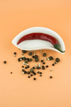 red hot chili pepper in plate on orange background