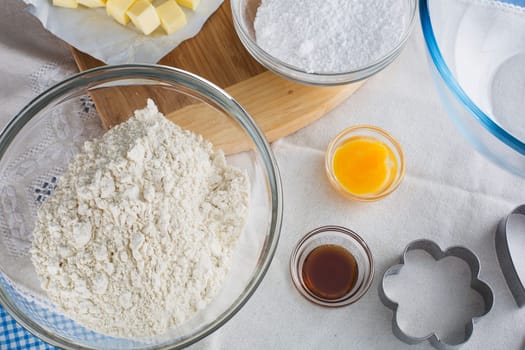 Baking ingredients including flour, egg yolk and vanilla extract, with cookie cutter.