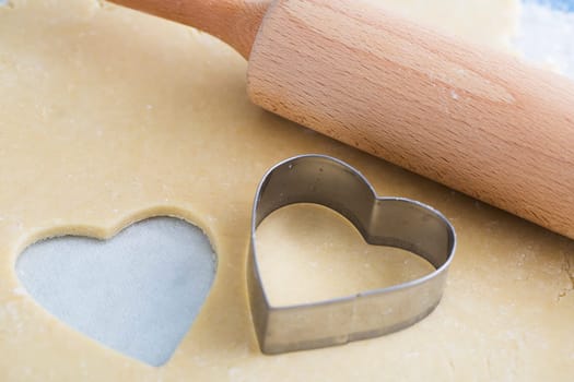 Dough rolled out with heart shape cut out, and heart shaped cookie cutter