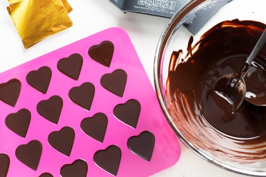 Bowl of warm chocolate and heart shaped form filled with chocolate.
