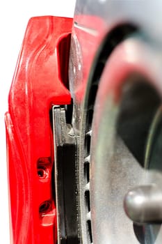 Closeup pads on disc car brake in red caliper isolated