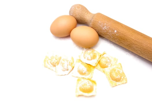 Ravioli with eggs and rolling pin on white background