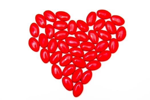 Sugared almonds arranged in heart on white background