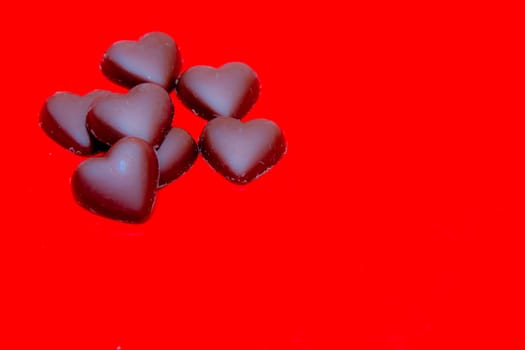 Chocolate hearts arranged on red background