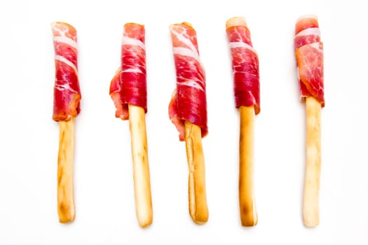 Slices of ham on grissini arranged on white background