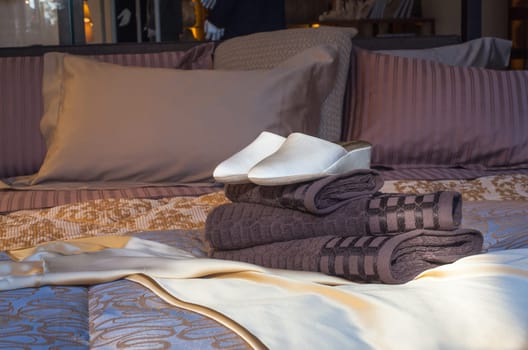 White female slippers on the towels in the bed