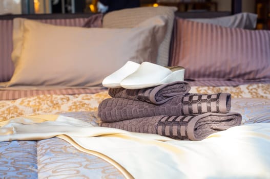 White female slippers on the towels in the bed