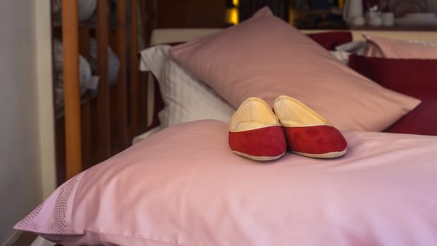 Red female slippers on the pink pillow