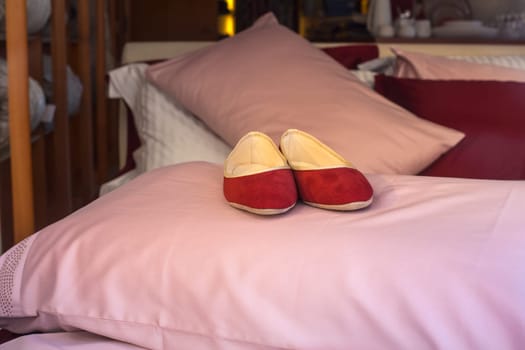 Red female slippers on the pink pillow