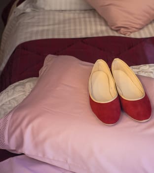 Red female slippers on the pink pillow