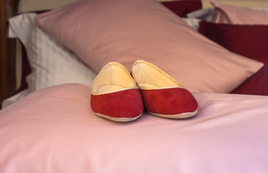 Red female slippers on the pink pillow