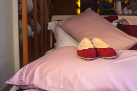 Red female slippers on the pink pillow