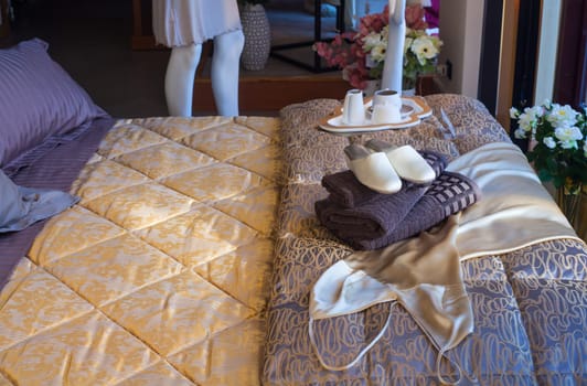 White female slippers on the towels in the bed