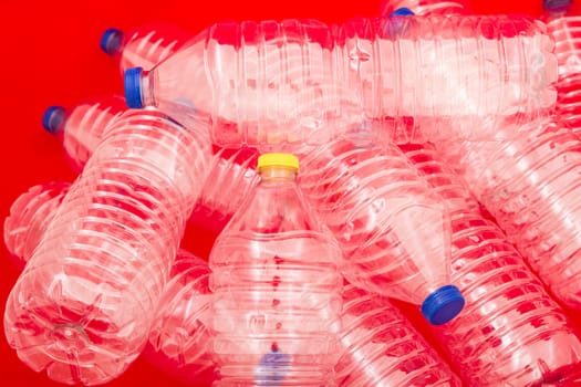 Empty bottles of mineral water, one with a different lid, with a red background.