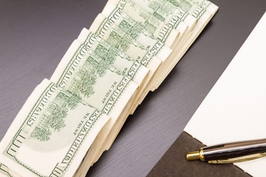 Lots of dollars with an open copybook.