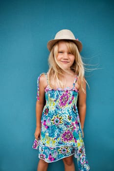Cute happy young girl wearing stylish hat outside against blue wall background