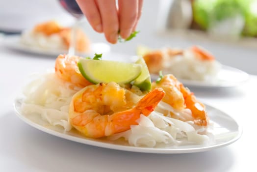 preparation of shrimp and rice pasta on a white plate,shallow dof.