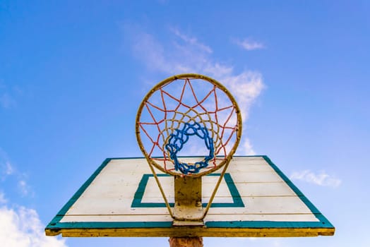 old style basketball basket with blue board in the background.