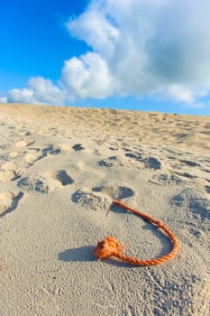 A fragment of the net rope on the beach, sky and white and grey clouds in the background.