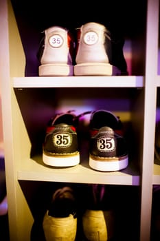 Old  bowling shoes placed in the cupboard, visible shoe sizes, fragment of wardrobe, vertical frame.