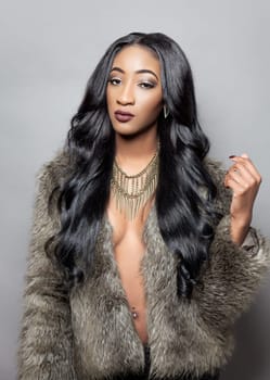 Beautiful black woman with long curly hair wearing a fur coat