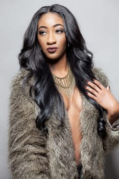 Beautiful black woman with long curly hair wearing a fur coat
