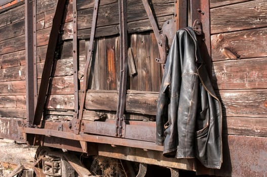 Vintage leather male jacket hanging on the wall of old wooden railway wagon as background