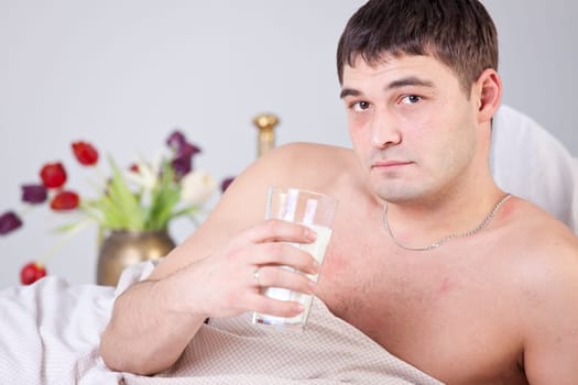 Sick man with glass milk on bed