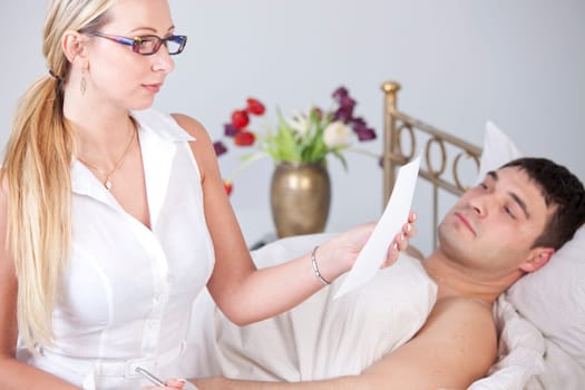 Woman reading medical report in front of sick man on the bed