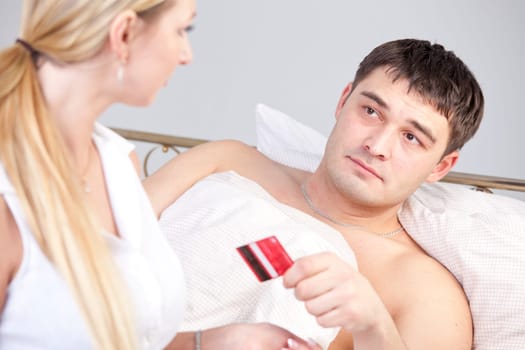 Man in bed holding credit card - paying for medical treatment or service