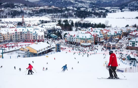 Mont-Tremblant, Canada - February 9, 2014: Skiers and snowboarders are sliding down the main slope at Mont-Tremblant. Mont-Tremblant Ski Resort is acknowledged, by most industry experts, as being the best ski resort in Eastern North America.