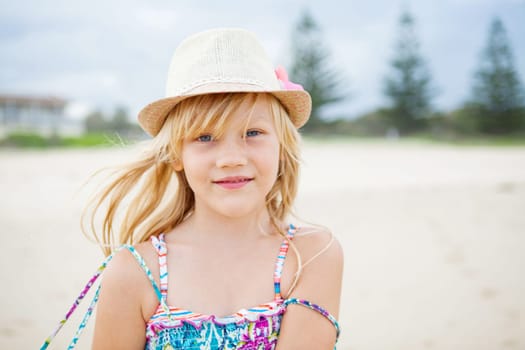 Portrait of cute young girl with summer dress and stylish hat at the beach