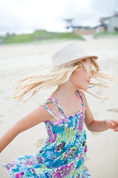 Cute young girl with summer dress and stylish hat having fun at beach