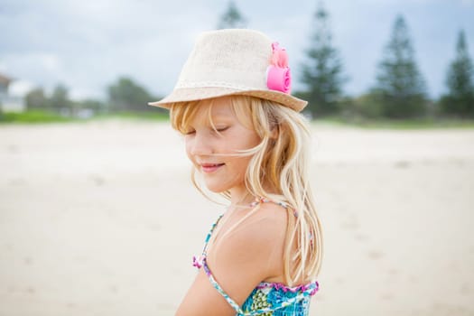 Portrait of happy cute young girl with stylish hat at the beach with eyes closed