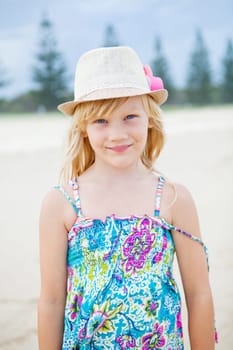 Portrait of cute young girl with summer dress and stylish hat at the beach