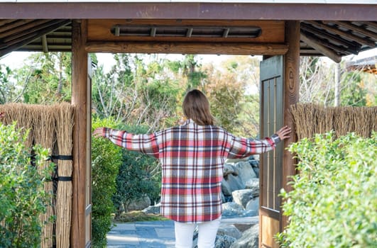 Woman in red plaid shirt enjoying nature walking in Japanese Garden