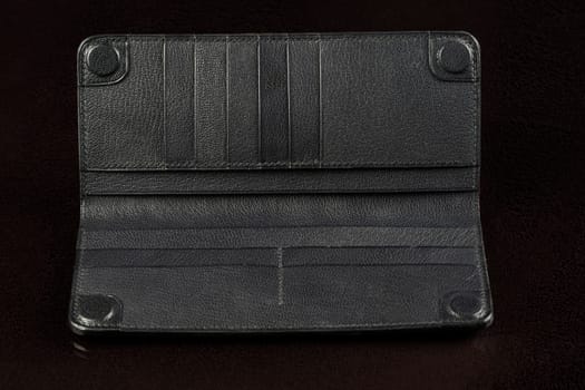 Black leather wallet on a black background.