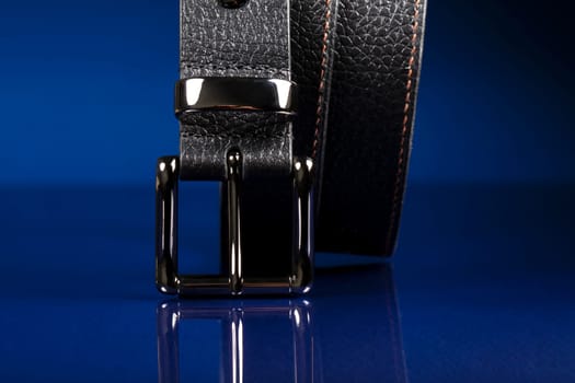 Black leather belt on a dark blue background.