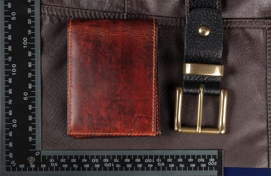 Leather goods purse and belt against the background of a ruler for cutting and sewing.