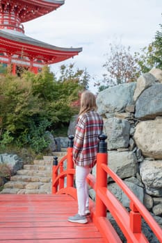 Woman in red plaid shirt enjoying nature walking in Japanese Garden with red pagoda