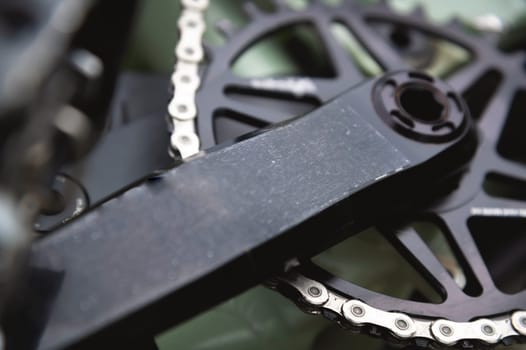 Close-up in shallow depth of field. Mountain bike pedals with large gear and chain. Cycling concept background.
